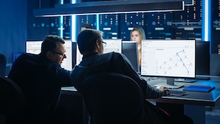 Two men looking at multiple monitors in control room