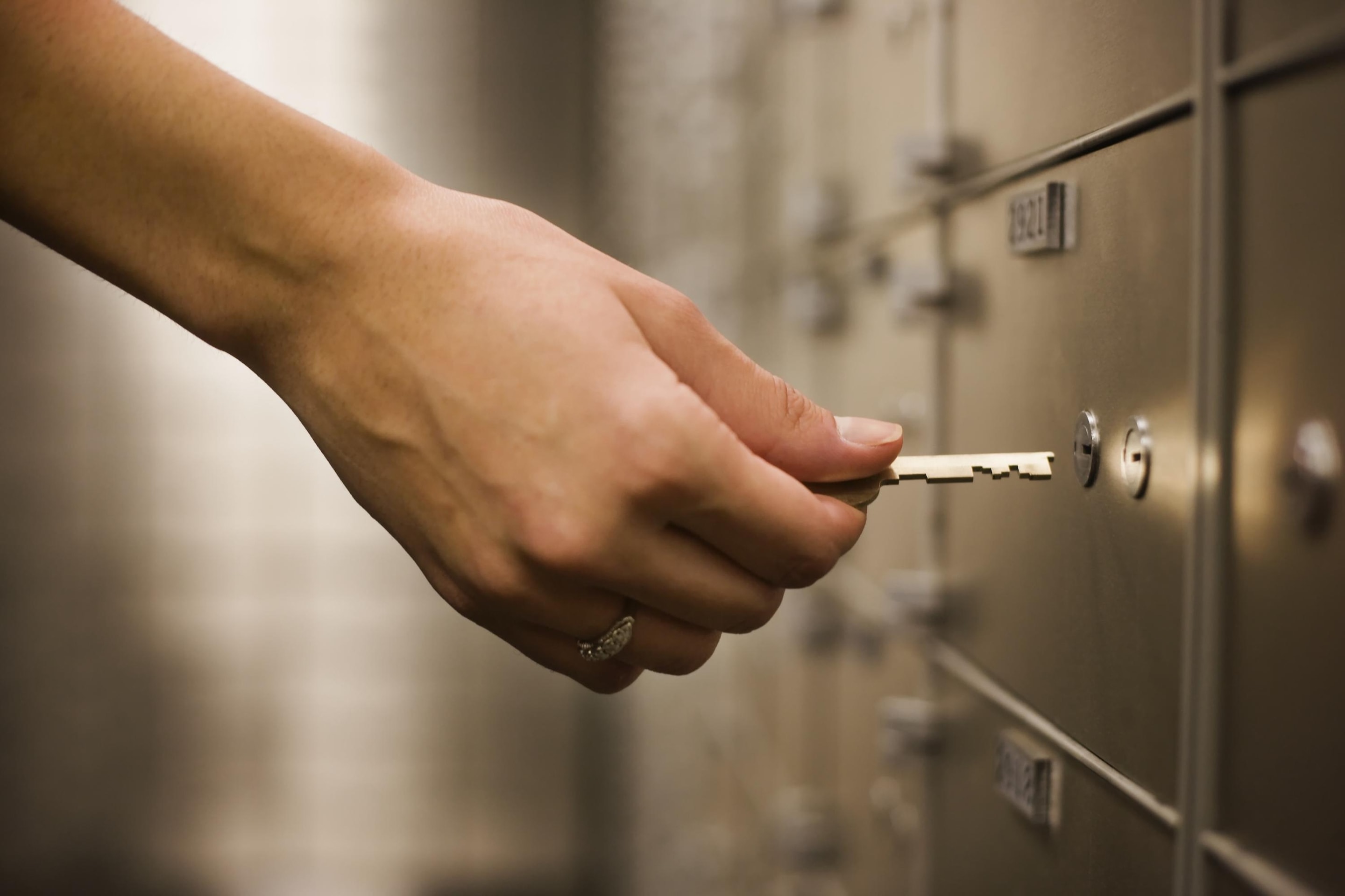 Hand inserting key into safety deposit box lock