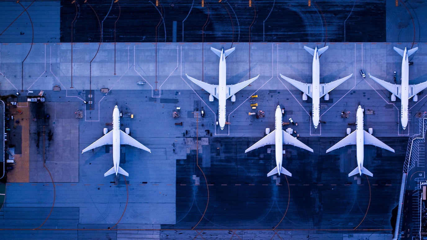 Overhead view of passenger jets lined up on runway