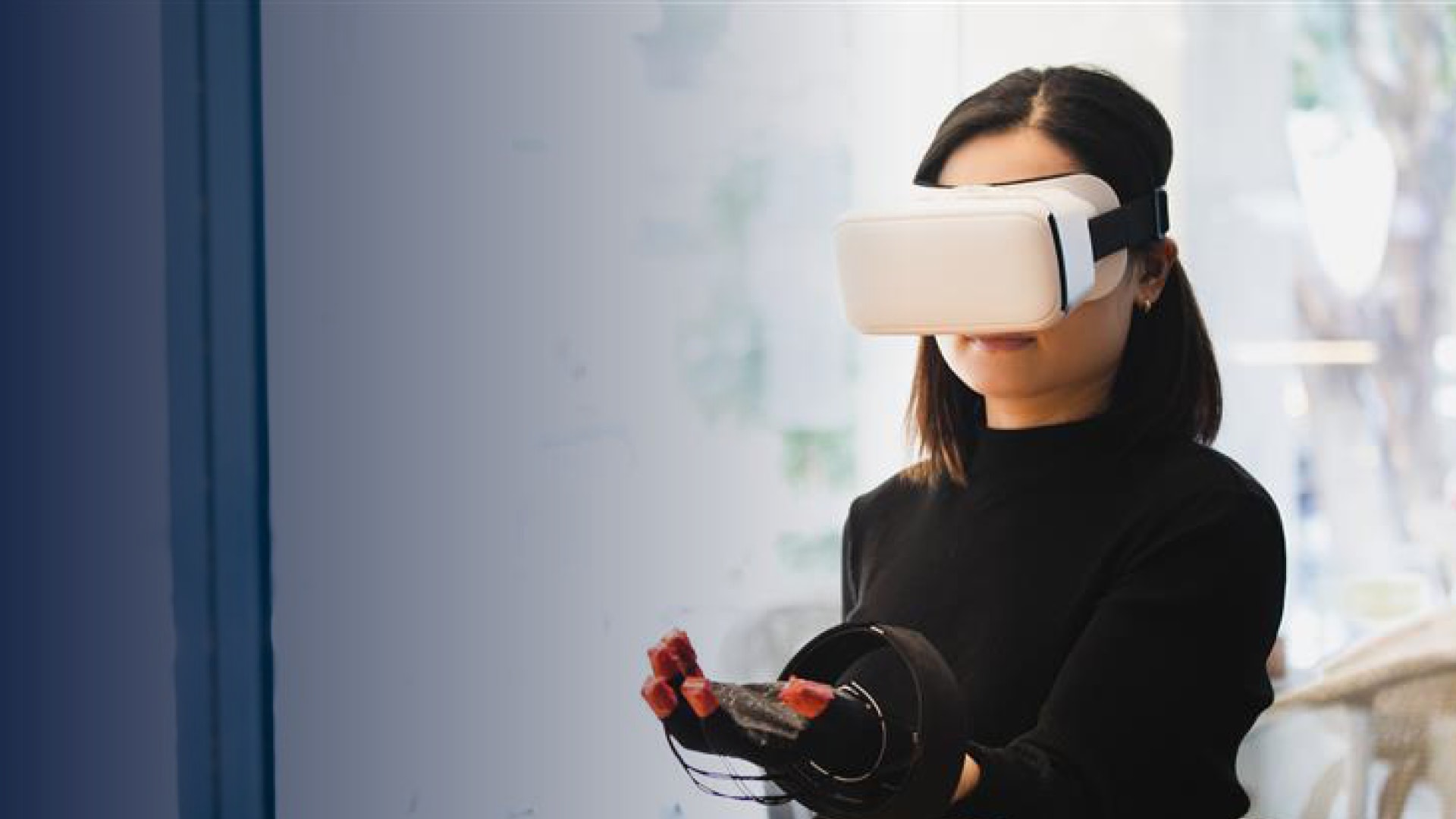 Woman wearing VR headset and haptic glove interacting with virtual environment indoors in lab rooms