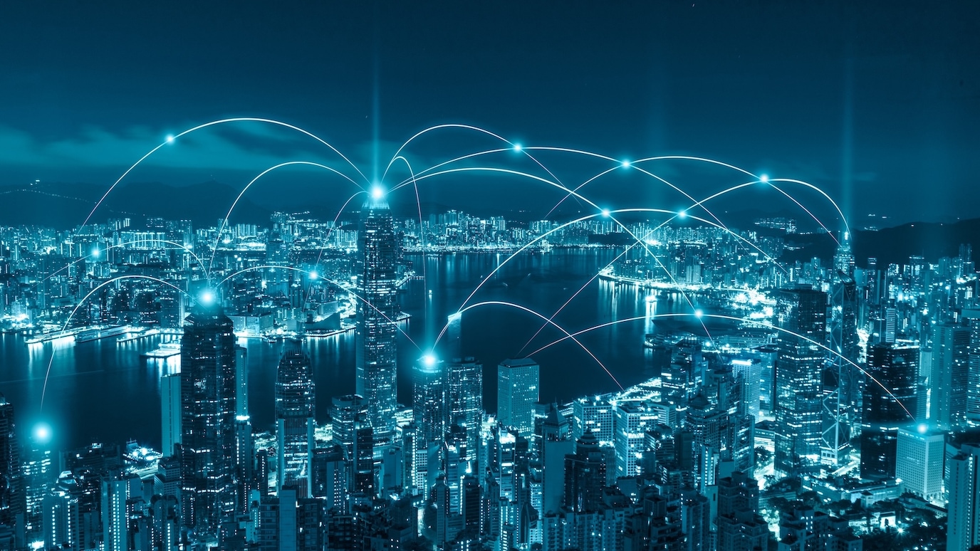Night city skyline with glowing network connections linking buildings across an urban waterfront.