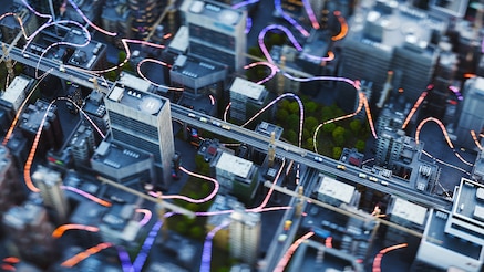 Overhead view of city buildings connected by trailers of light 