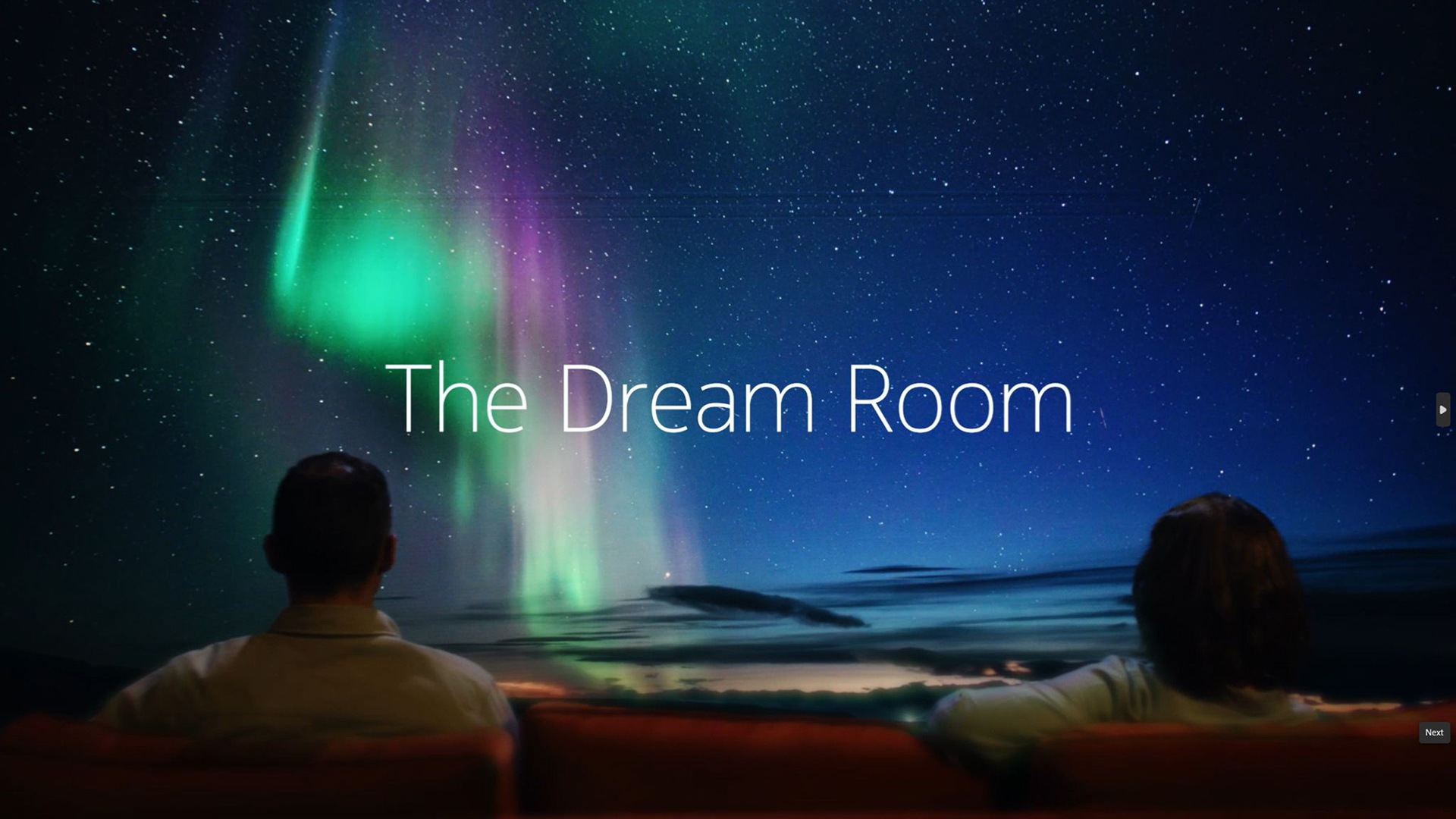 Two people on movie seats looking at the Norther Lights on a screen