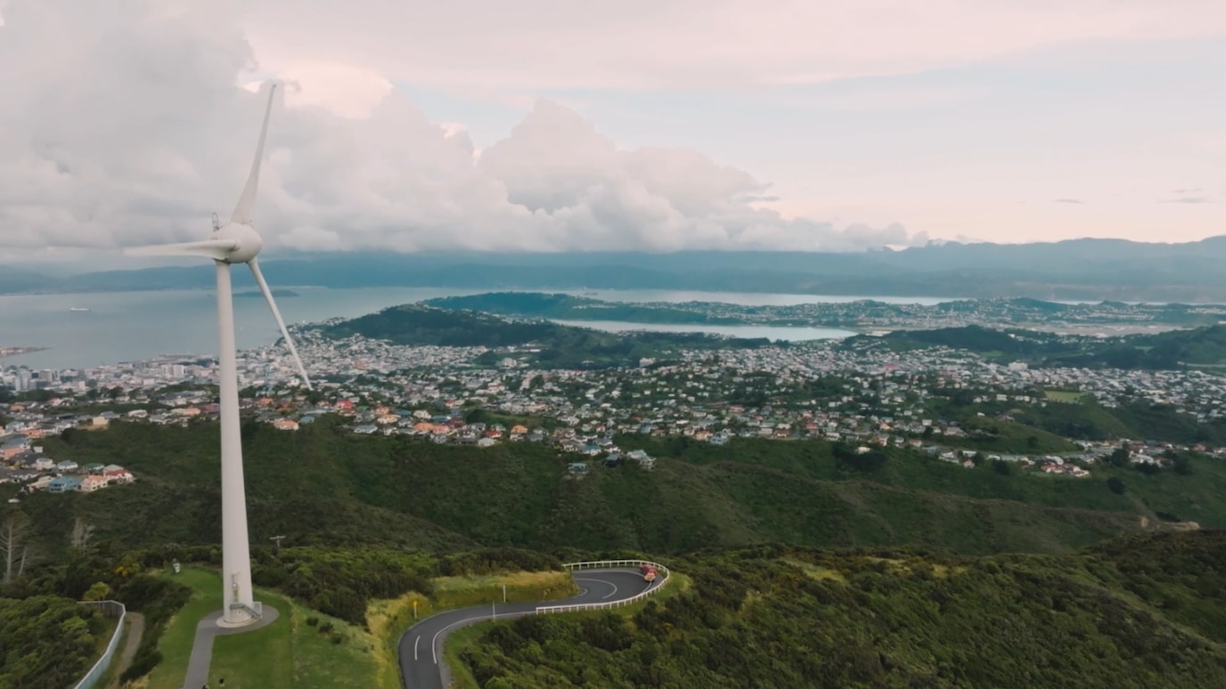 Wind turbine on hilltop overlooking town by the sea