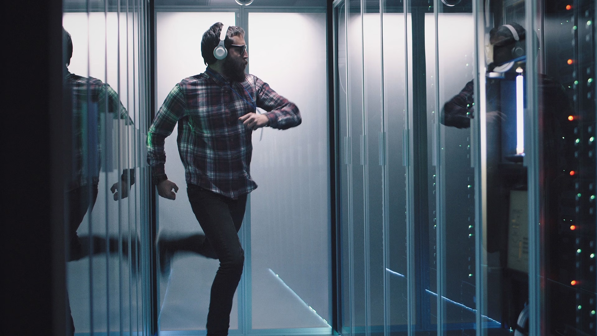 Man dancing while wearing headphones inbetween server cabinets 