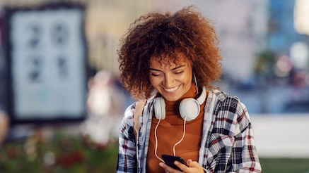 Woman with headphones around her neck looking at smartphone