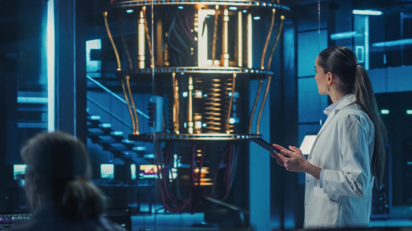 Woman in lab coat stood in front of quantum computer