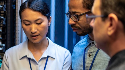 Three people talking in front of server cabinets