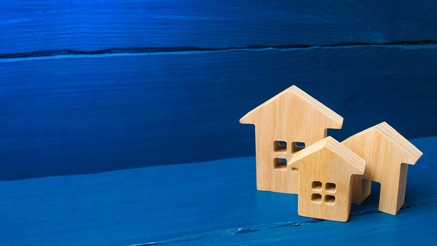 Stylised carvings of house in wood agains background of planks painted blue