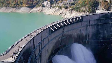 People on top of dam observing water flow below
