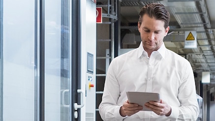 Man looking at tablet device in front of server room door
