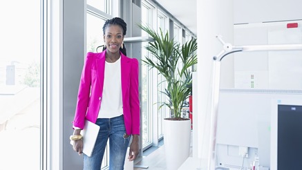 Woman in office holding laptop under arm