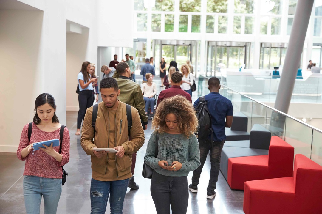 students walkin university campus using tablets