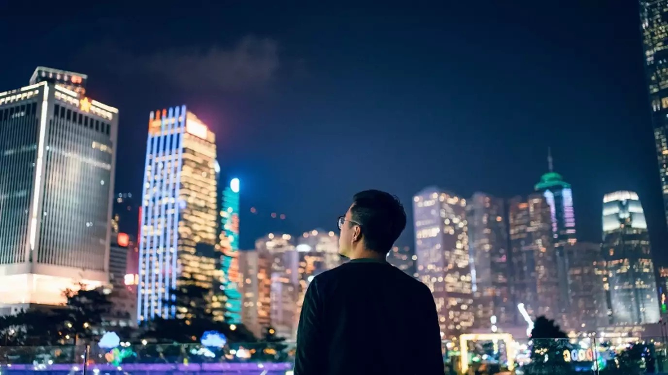 Asian man looking at skyscrapers at night