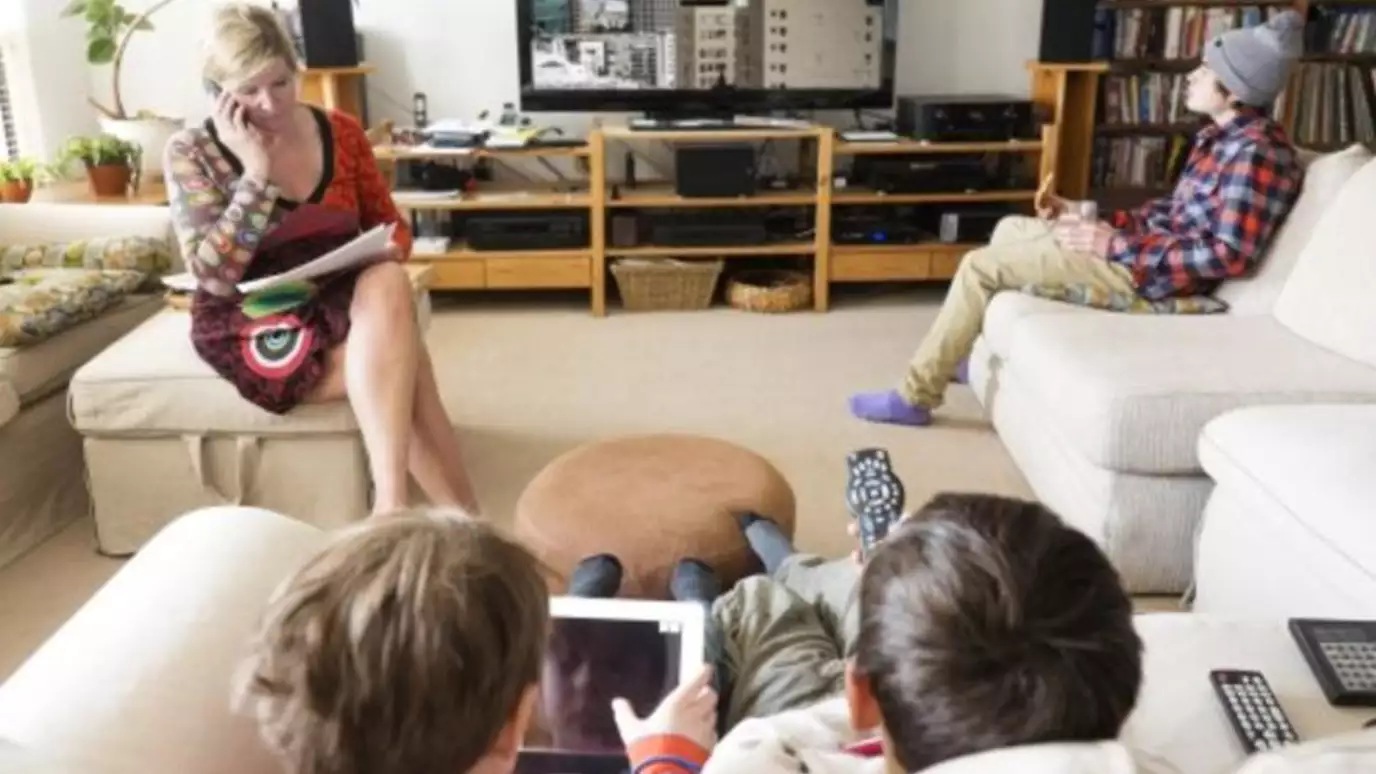 Family in living room watching TV and using wireless devices