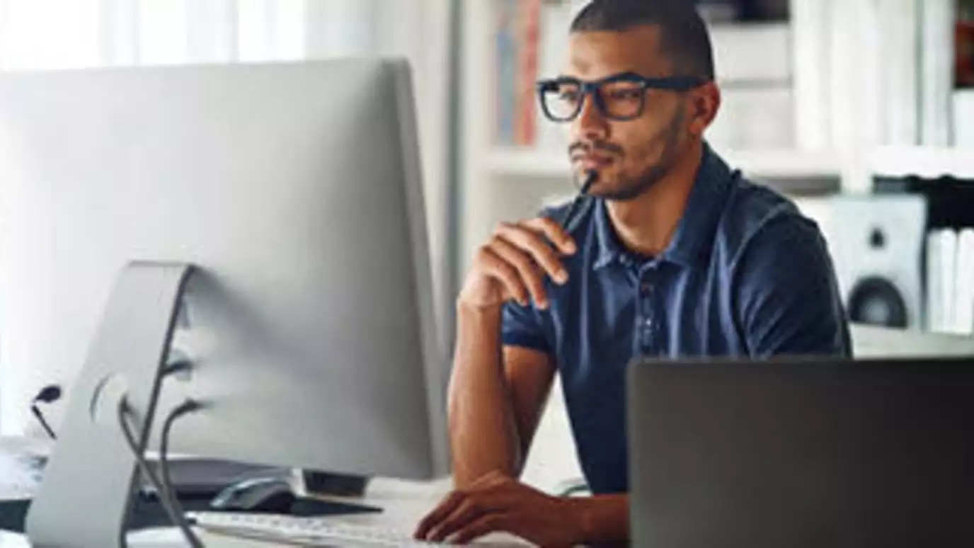 Man facing working at desk, looking at monitor