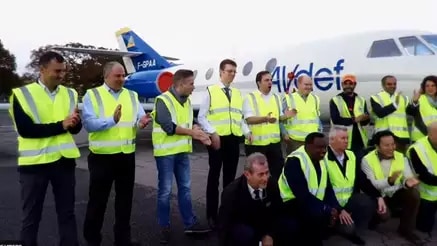 Airport workers standing in front of plane in yellow hi-vis vests