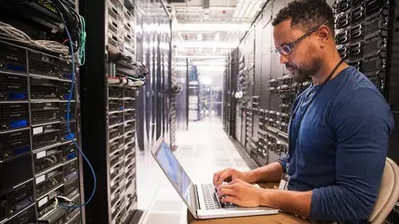 Engineer working on laptop connected to servers
