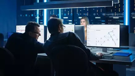 Two men looking at multiple monitors