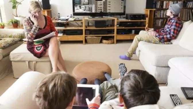 Family in living room watching TV and using wireless devices