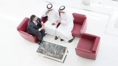 An image of three people sitting on red couches discussing something.
