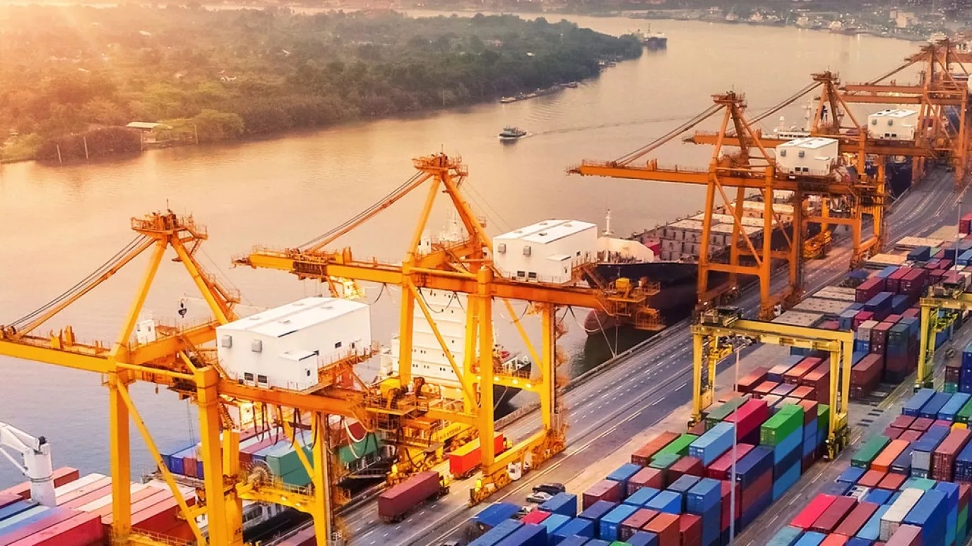 A picture of harbour cranes and containers by a river.