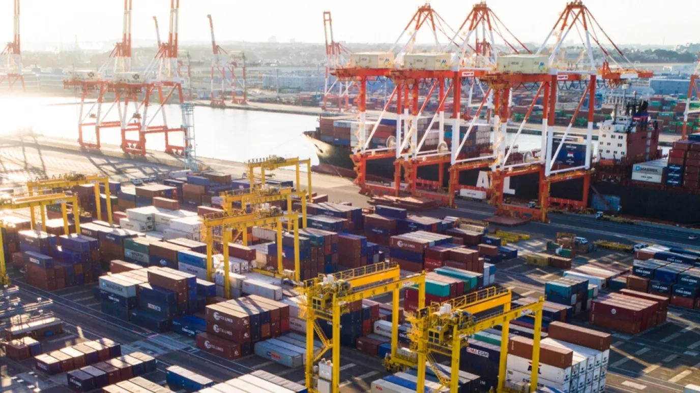 An image of a port with containers, cranes and a ship.