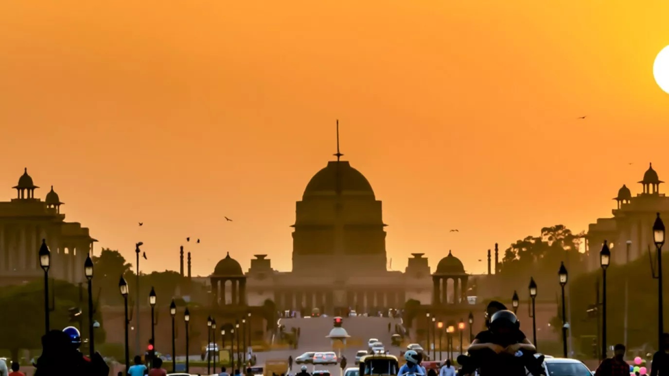 A cityscape in India with the sun in the background.