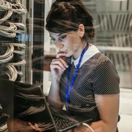 Engineer looking at laptop connected to server rack