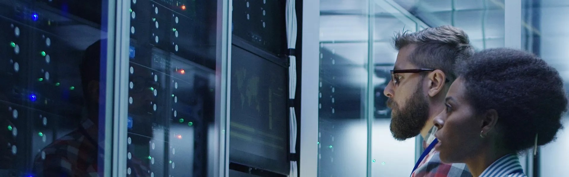Two engineers looking at screen next to server rack