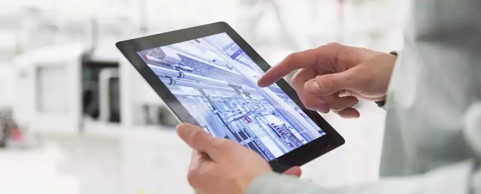 Photo of a person using a tablet to manage an automated factory