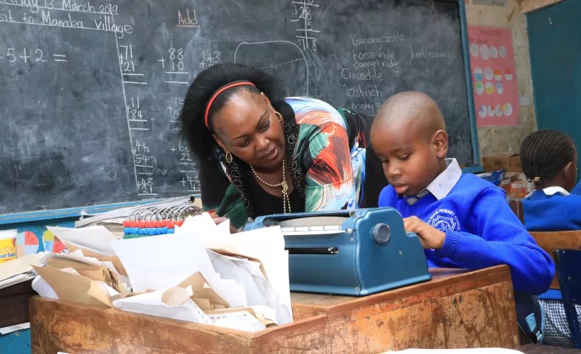 Madam Beth guiding Wesley through his class work. UNICEFKenya/2019/Ngochi