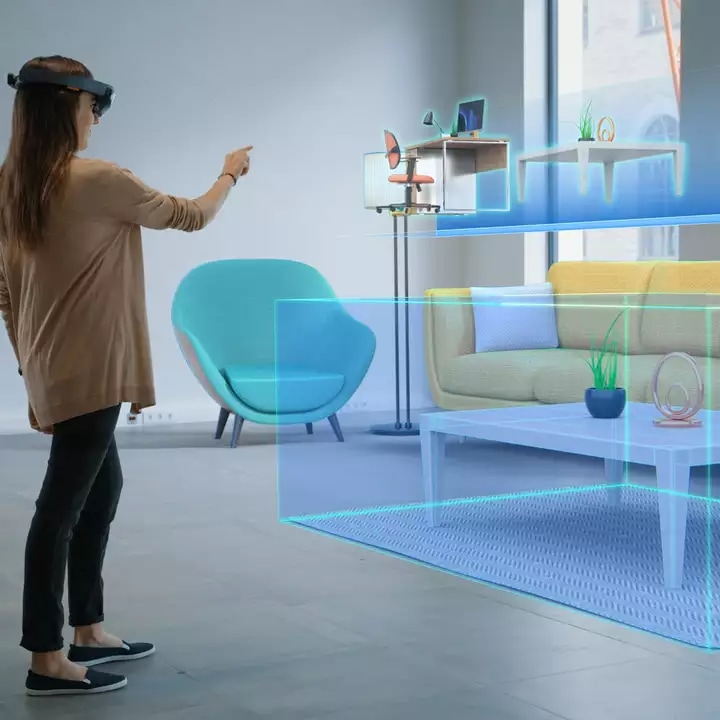 A woman using a VR headset to view furniture and layout options in a room