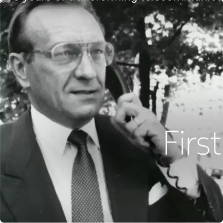 Black and white photograph of man in suit making a GSM call