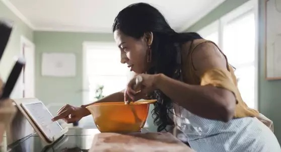 woman checking tablet while cooking