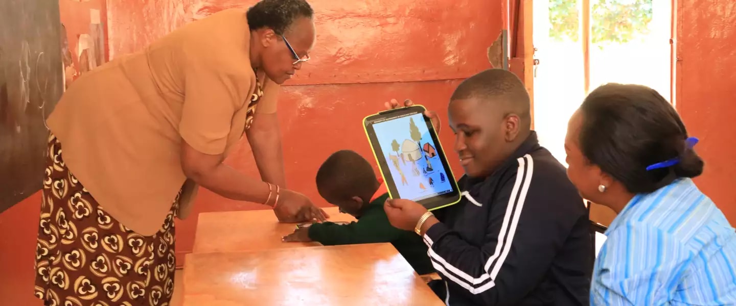 Teacher Jane Njoroge looks on as Frank from Mugumoini Primary School in Thika Town uses his digital tablet. /  ©UNICEFKenya/2019/Ndinda