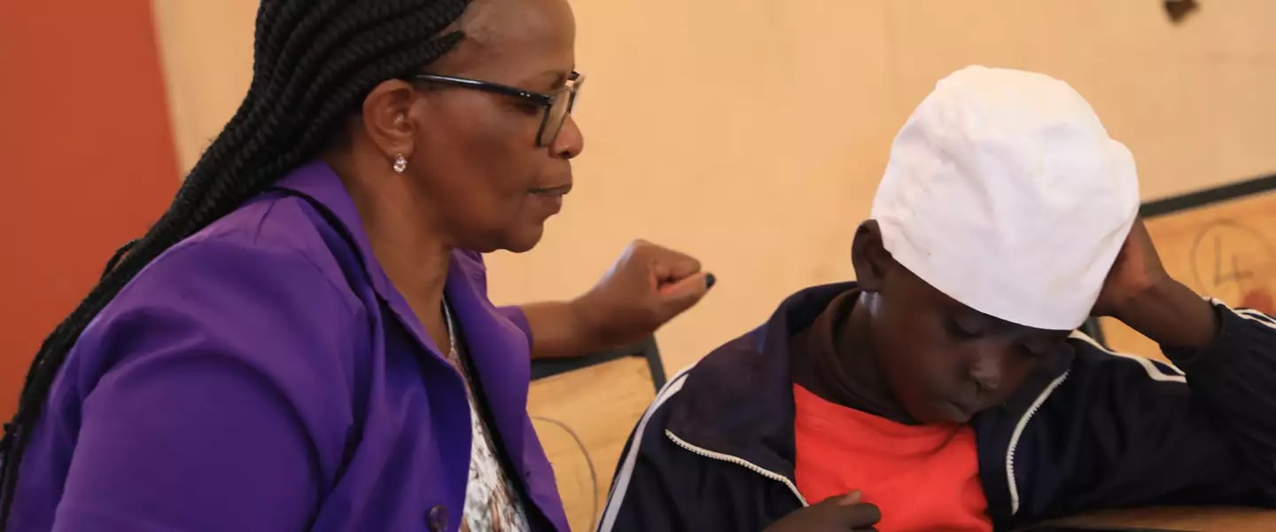 Teacher Jane Njoroge looks on as Frank from Mugumoini Primary School in Thika Town uses his digital tablet. /  ©UNICEFKenya/2019/Ndinda