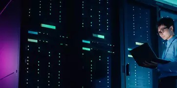a bank of data center server racks with a man using an ipad.